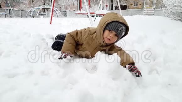 4k视频快乐微笑幼儿男孩在冬季公园玩耍并在镜头中投掷雪球视频的预览图