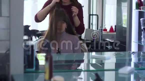 用手和梳子形成头发链用于头发造型发型师长着一个时髦的节日发型视频的预览图
