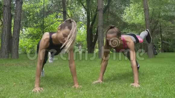 两位年轻的美女正在公园里做木板运动健身模特们正在锻炼身体视频的预览图