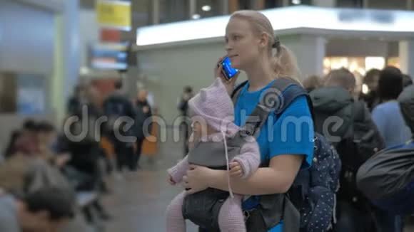 妈妈带着女儿在机场等着女人在手机上说话视频的预览图