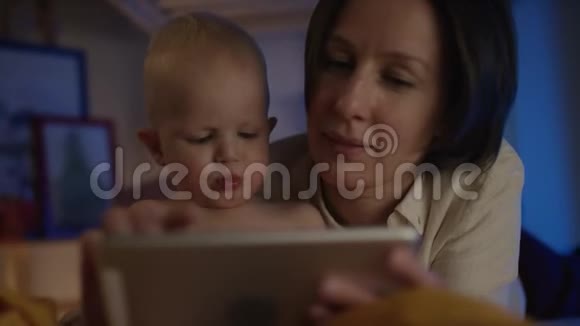 母亲给婴儿看书躺在床上画着不同的图画让他一起放松视频的预览图