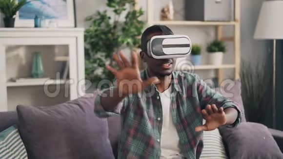 非洲裔美国年轻人在玩增强现实眼镜游戏独自在家玩戴着耳机视频的预览图