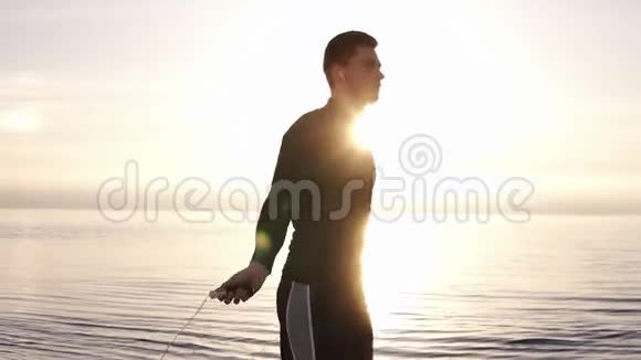 高个子肌肉发达的年轻人在海边用跳绳锻炼从事户外运动的年轻人视频的预览图