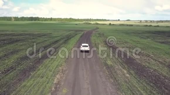 空中白色汽车在田野间沿着地面轨道行驶视频的预览图