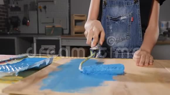 一个画蓝色的小女孩的特写镜头用滚筒画板快关门慢动作高清高清视频的预览图