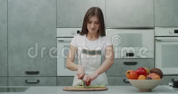 在现代厨房设计中一位漂亮的女士在镜头前做饭切一些蔬菜视频的预览图