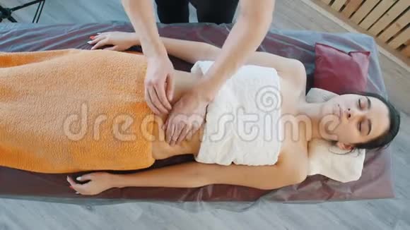 一个按摩师为一个年轻的女人一个放松的腹部按摩和调整运动视频的预览图