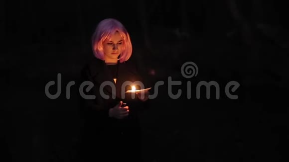 美丽的白种人年轻女孩粉红色的头发在黑暗中拿着一张燃烧的纸视频的预览图