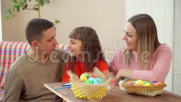 爸爸妈妈看着女儿然后同时在镜头中展示复活节彩蛋在前景是视频的预览图