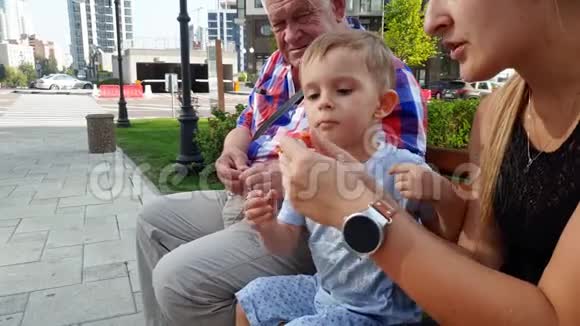 幼儿妈妈爷爷幼儿男孩在公园长椅上投放玩具直升机4k视频视频的预览图
