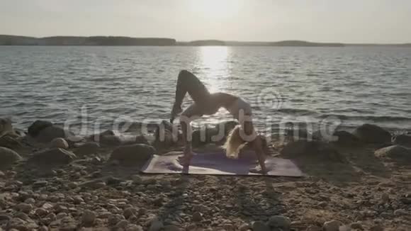 海洋背景上的年轻运动美女健身女孩在海滩晨练视频的预览图