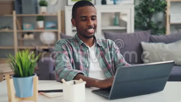 成功的非裔美国人自由职业者使用笔记本电脑在工作室的办公桌上看屏幕视频的预览图