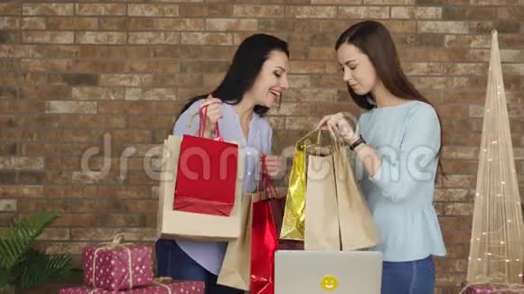 两个女朋友互相展示他们的购买黑色星期五概念视频的预览图