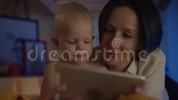 妈妈给躺在床上的可爱宝宝看书给他看不同的照片给他看流动相机视频的预览图
