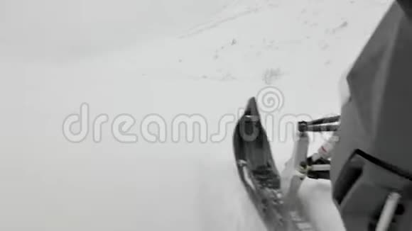 灰色的雪上摩托速度沿着雪山之间的山坡视频的预览图