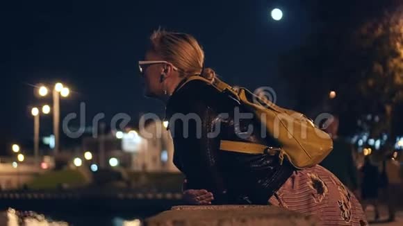 这个女孩晚上站在城市的滨水上向前看视频的预览图