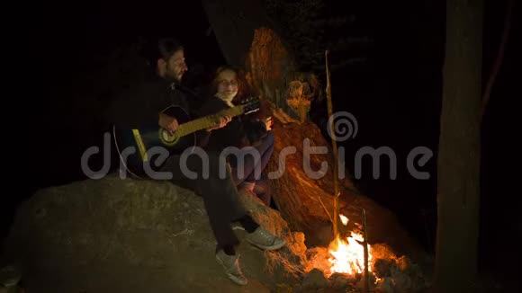 年轻夫妇在篝火晚会上演奏吉他视频的预览图