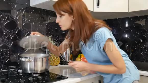 年轻的黑发女人站在厨房的炉子旁边黑色的背景闻到了她的饭菜的香味视频的预览图