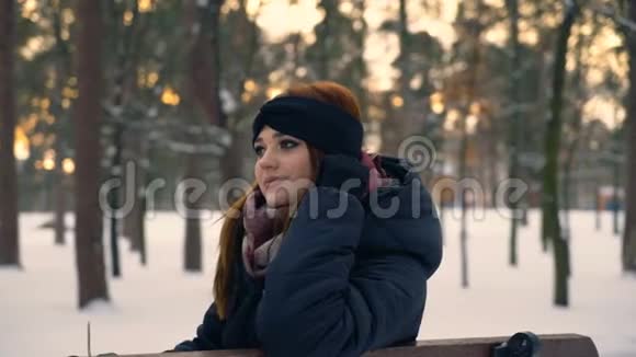 雪域公园里的红姜发女坐在长凳上4K视频的预览图