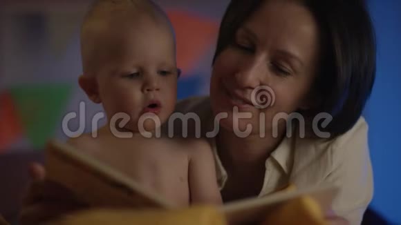 可爱的宝宝和妈妈一起坐在床上为他读童话视频的预览图