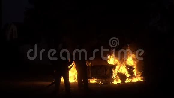两个消防队员站在燃烧的汽车前慢镜头视频的预览图