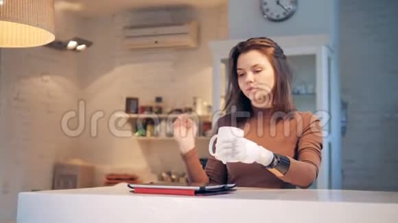 戴着仿生手的微笑女士正从杯子里喝着酒操作着一块平板电脑视频的预览图