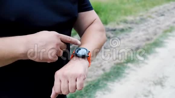 身穿黑色制服的运动员举起双手手里拿着一只智能手表触摸着视频的预览图