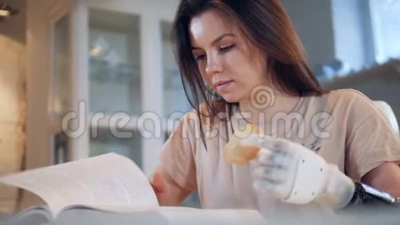 一位长得好看的女士手里拿着一只仿生手正在看书吃着一块饼干视频的预览图