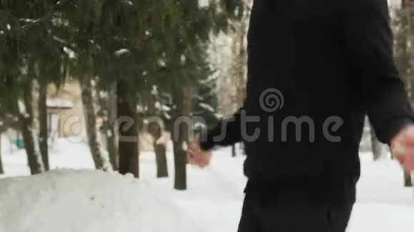 穿着黑色运动服的年轻人在寒冷的天气里在一个白雪覆盖的公园里做运动跳绳视频的预览图