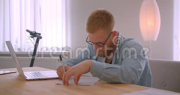戴眼镜的成年红发白种商人在办公室室内签署文件的特写照片视频的预览图