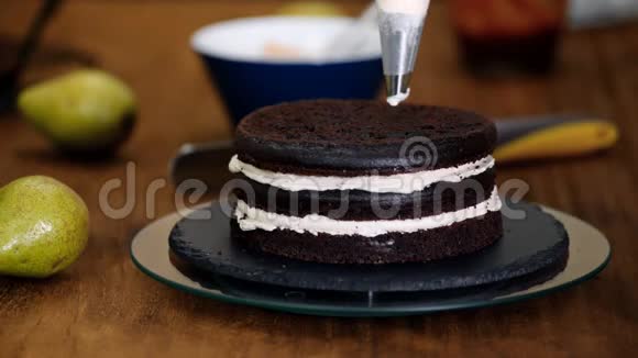 糖果女人用梨馅做巧克力蛋糕面包师女人把奶油挤在蛋糕上视频的预览图
