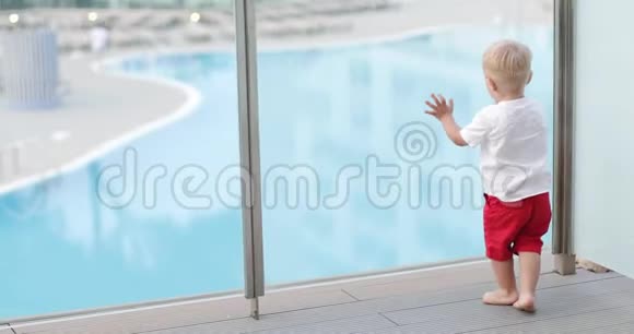一个快乐的男孩带着糖果在游泳池背景下的夏天露台上跑来跑去视频的预览图