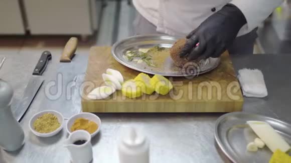 专业厨师手戴黑色乳胶手套在金属板上搓一块小牛肉腌肉餐桌视频的预览图