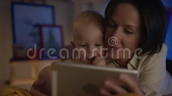 妈妈给躺在床上的宝宝看平板书给他看不同的图片给他近距离的治疗视频的预览图