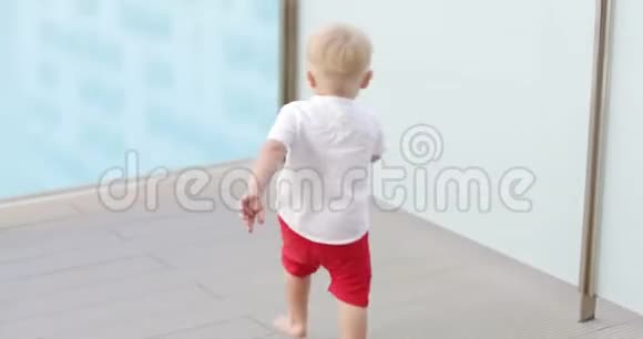 一个带着糖果的可爱宝宝在夏日露台上奔跑背景是一个游泳池视频的预览图