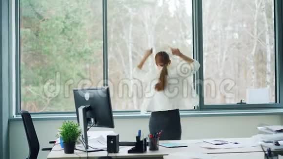 这位玩得很开心的年轻女士正在办公室里跳舞她一边甩头发一边摘下眼镜一边笑一边走视频的预览图