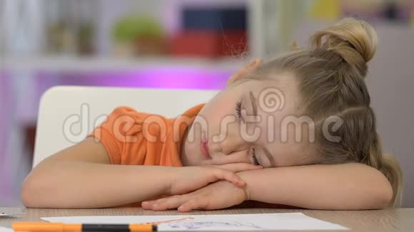 女孩睡在桌边微笑着画画后很累做了个好梦视频的预览图