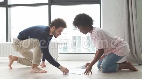 年轻的多种族夫妇坐在地板上检查账单学习文件准备财务报告视频的预览图