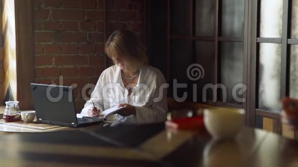 成熟的女人坐在咖啡店里工作视频的预览图