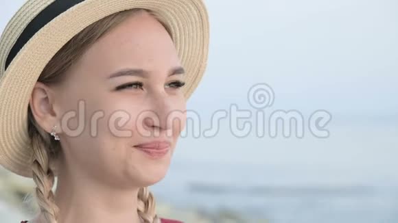 一个漂亮的白种人年轻女子戴着一顶草帽扎着辫子的大特写肖像使帽子挺直视频的预览图