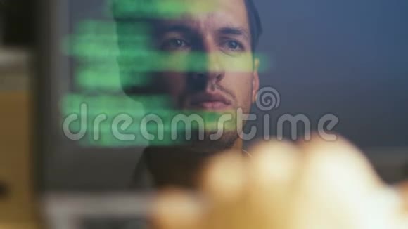 一个黑客程序员在笔记本电脑前工作的双重曝光照片监视器中的反射开发人员编写绿色代码视频的预览图