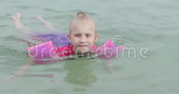 快乐的女孩手臂上有褶边漂浮在海里视频的预览图