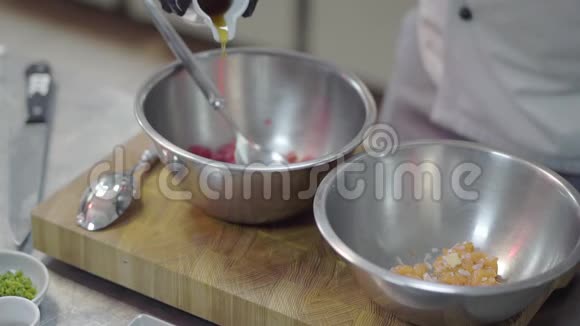 一位经验丰富的厨师戴着黑色烹饪手套用橄榄油倒入红鱼沙拉厨师慢慢做饭视频的预览图