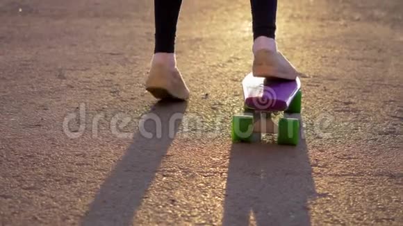 穿着白色运动鞋的女孩骑着滑板在柏油路上推着自己斯洛莫视频的预览图