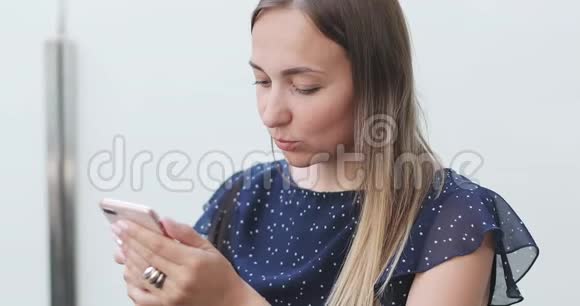 一位留着长发的年轻女子坐在一个开放的阳台上在手机上留言视频的预览图