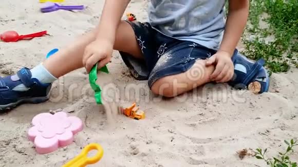 可爱的幼儿男孩在公园的沙箱里用铲子挖沙子的4k特写视频视频的预览图