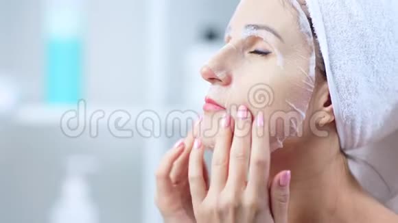 年轻女性用化妆纺织品面膜护理面部皮肤特写概念视频的预览图