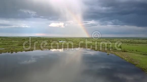 美丽的彩虹和蓝色的云彩反射在平静的湖面上视频的预览图