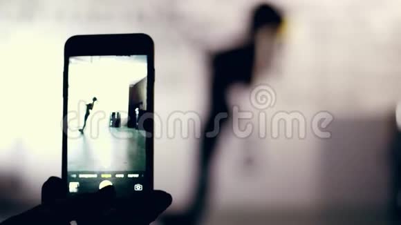 特写镜头智能手机监视器拍摄一个黑暗的人物一个女人的轮廓在TRX循环陷阱在视频的预览图