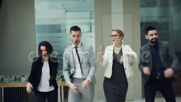 多莉拍摄的吸引年轻人的商业团队一起在大厅跳舞拍手和微笑公司党视频的预览图